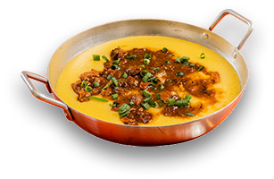 Fotografia da polenta caipira em panela: polenta amarela com ragú de carne e cebolinha.